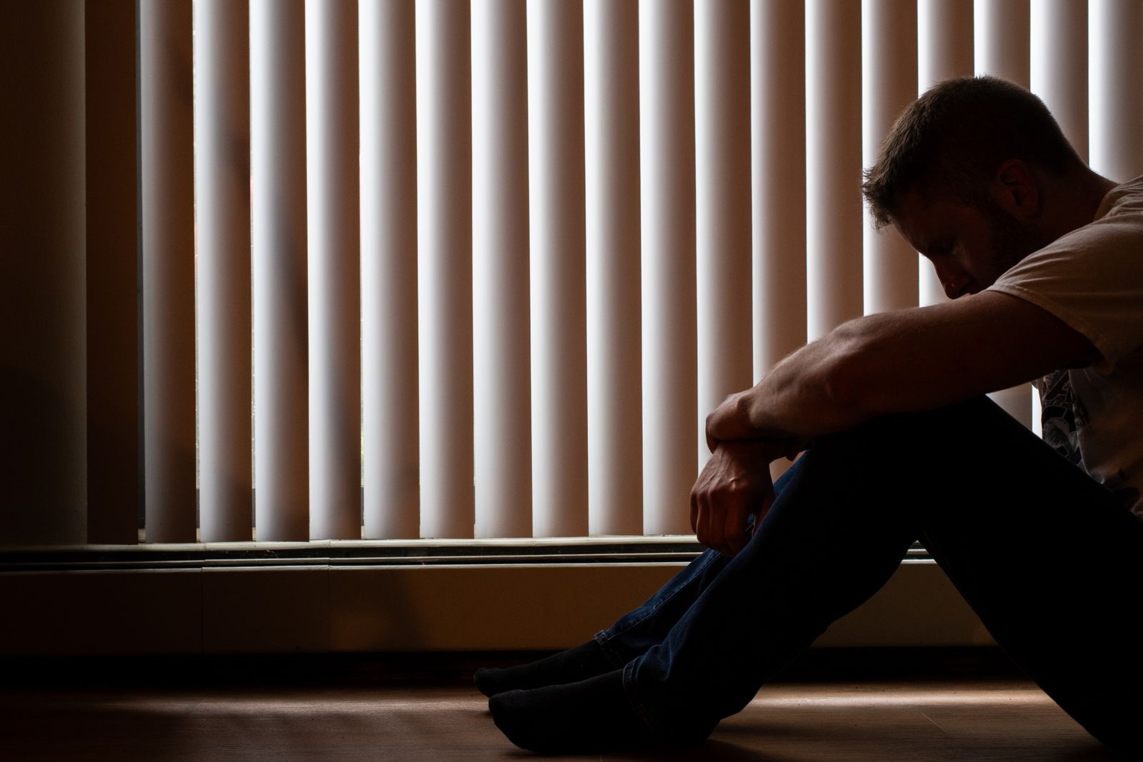 Man sitting alone by a window looking overwhelmed by anxiety
