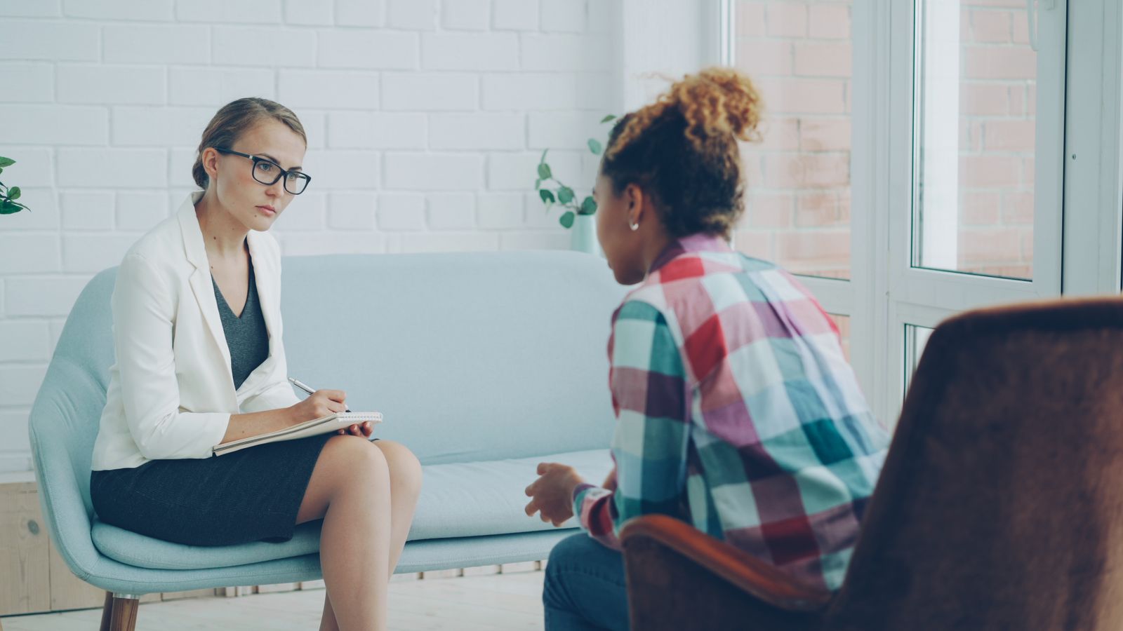 Therapist taking notes while listening to a client during a counseling session