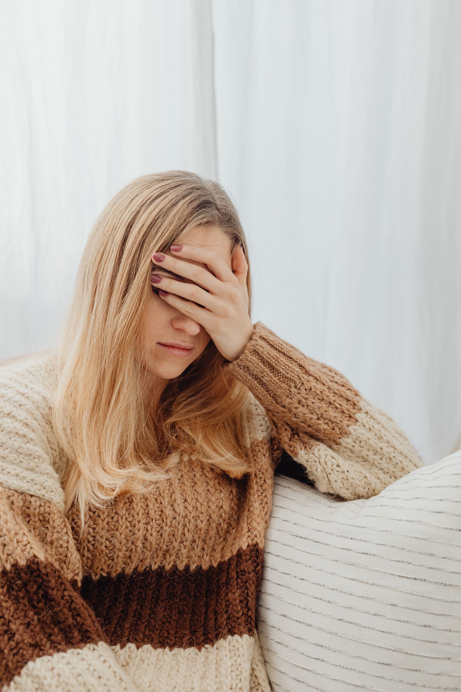 Woman sitting with her hand over her eyes, experiencing depression